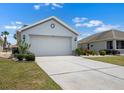 Two car garage with concrete driveway and mature landscaping at 1112 Jasmine Creek Ct, Sun City Center, FL 33573