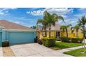 Charming yellow home with a blue garage, lovely landscaping, and well-maintained front yard at 11457 Captiva Kay Dr, Riverview, FL 33569