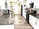 Modern kitchen with granite countertops, black appliances, hardwood floors, and ample white cabinetry at 1165 Falcon Dr, Dunedin, FL 34698