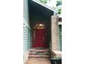 Inviting front entrance with a red door and brick accents, framed by lush greenery at 11783 Ashley Ct, Seminole, FL 33772