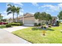 A cozy single-story home with a screened garage, lush landscaping, and a brick paver driveway at 1231 Corinth Greens Dr, Sun City Center, FL 33573