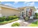Enclosed sunroom with tiled entryway, manicured landscaping, and light colored stucco exterior at 1231 Corinth Greens Dr, Sun City Center, FL 33573