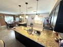 Bright kitchen featuring granite countertops, pendant lighting, dark cabinets, and stainless steel appliances at 13924 Pathfinder Dr, Tampa, FL 33625