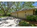 Spacious three-car garage with tan doors and exterior lights surrounded by green landscaping at 1816 Curry Rd, Lutz, FL 33549