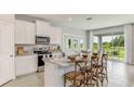Modern kitchen featuring white cabinetry, stainless steel appliances, and a spacious island with seating at 2250 Sienna Spruce St, Wesley Chapel, FL 33543