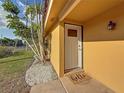 Charming front entrance with a 'hello' mat, yellow siding, and well-maintained landscaping at 2600 N Paula Dr # 2B, Dunedin, FL 34698
