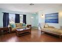 Inviting living room featuring hardwood floors, a comfortable sofa, and large windows providing natural light at 2964 Catherine Dr, Clearwater, FL 33759