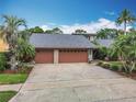Spacious home with a three-car garage, a gray roof and beautiful landscaping at 3168 Masters Dr, Clearwater, FL 33761