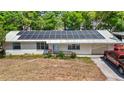 Single-story home featuring a metal roof with solar panels, an accessible ramp, and a well-lit driveway at 38351 7Th Ave, Zephyrhills, FL 33542