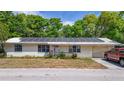 Single-story home featuring a metal roof with solar panels, an accessible ramp, and a well-lit driveway at 38351 7Th Ave, Zephyrhills, FL 33542