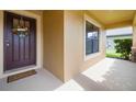 Inviting front porch featuring a decorative welcome mat and a window that offers a view to the greenery at 4725 Royal Birkdale Way, Wesley Chapel, FL 33543