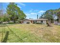 Inviting single-story home featuring a lush green lawn and mature trees in front at 5065 Shore Acres Ne Blvd, St Petersburg, FL 33703