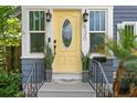 A bright yellow front door flanked by matching planters and stylish outdoor lanterns at 930 23Rd N Ave, St Petersburg, FL 33704