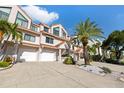 Inviting townhome boasts an attached garage and well-maintained landscaping with mature palm trees at 1206 Gulf Blvd # C, Indian Rocks Beach, FL 33785