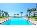 Large outdoor pool with lounge chairs and umbrellas surrounded by lush greenery and waterfront views at 1301 Gulf Blvd # 107, Clearwater Beach, FL 33767