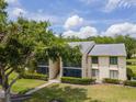 View of the neutral-toned exterior of this two-story condominium building showcasing a large shade tree and lush landscaping at 1400 Pine Glen Ln # B2, Tarpon Springs, FL 34688