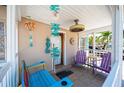 Inviting front porch with colorful furniture and coastal decor, creating a relaxing outdoor space at 1507 Legion Ln, Indian Rocks Beach, FL 33785