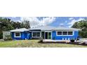 A charming exterior view of the blue home showing landscaping, plants, silver roof and impact windows at 2810 Norwood Ln, Venice, FL 34292