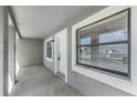 A porch featuring a gray exterior wall and white door, complemented by neutral trim and a large window at 3208 E 8Th Ave, Tampa, FL 33605
