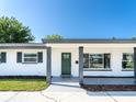 Close-up of the front porch with a modern green door, contemporary hardware, and freshly painted columns at 352 79Th Ne Ave, St Petersburg, FL 33702