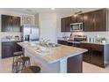 Kitchen featuring dark wood cabinets, stainless steel appliances, and an island with seating at 35670 Lockman Way, Zephyrhills, FL 33541