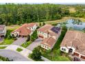 Aerial view of home with tile roof, landscaping, a pond, and situated among other houses at 4024 Woods Rider Loop, Odessa, FL 33556