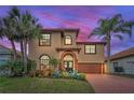 Charming two-story home with lush tropical landscaping, tile roof, and brick driveway at sunset at 5807 Cay Cove Ct, Tampa, FL 33615