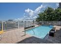 Community outdoor swimming pool area features brick pavers, secure white fencing, and serene water views at 600 Bayway Blvd # 304, Clearwater, FL 33767