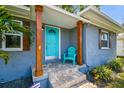 Inviting front porch with light blue door, wood pillars, stone steps and green chair at 6207 Gulfport S Blvd, Gulfport, FL 33707