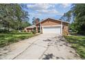 Single-story home with an orange facade, a two-car garage, and a well-maintained green lawn at 6938 Coronet Dr, New Port Richey, FL 34655