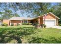 Well-maintained single-story home featuring an attached two-car garage, green lawn, and manicured landscaping at 6938 Coronet Dr, New Port Richey, FL 34655