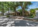 Residential street view featuring a well-maintained home with mature trees and lush landscaping at 740 Crystal Dr, Palm Harbor, FL 34683