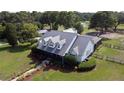Aerial view of a beautifully landscaped home with a dark metal roof, mature trees, and a large lawn at 10101 Bryant Rd, Lithia, FL 33547