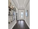 Inviting entryway with a tray ceiling, dark hardwood floors, and decorative shelving with Gathering photos at 11743 Lake Lucaya Dr, Riverview, FL 33579