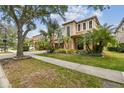 Charming two-story home featuring a two-car garage, lush landscaping with palm trees on a sidewalk street at 20347 Chestnut Grove Dr, Tampa, FL 33647