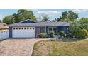 Charming one-story home featuring lush landscaping, beautiful curb appeal, and a brick-paved driveway at 206 Timberview Dr, Safety Harbor, FL 34695