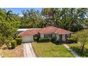 Inviting single-story home featuring a manicured lawn, a driveway leading to a garage, and mature landscaping at 219 Park S Cir, Dunedin, FL 34698