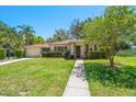 Charming single-story home with a well-manicured lawn, lush landscaping, and decorative shutters and front door at 219 Park S Cir, Dunedin, FL 34698