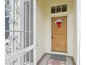 Close-up of a wood front door with a red bow and security gate at 2602 Novack Ct, Sun City Center, FL 33573