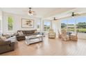 Bright living room featuring wood floors, two sofas, and large windows overlooking the lake at 2602 Novack Ct, Sun City Center, FL 33573