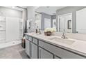Bright bathroom featuring double sinks with modern fixtures and a walk-in shower with glass doors at 33091 Osprey Peak Way, San Antonio, FL 33576