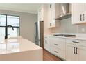 Bright kitchen featuring white cabinets, stainless steel appliances, quartz countertops, and hardwood floors at 3310 W Rogers Ave, Tampa, FL 33611