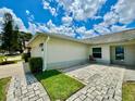 Side exterior view featuring a paved walkway, green lawn, and a cozy outdoor seating area with view of the sky at 3944 102Nd N Pl, Clearwater, FL 33762