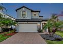 Charming two-story home featuring a brick driveway, two-car garage, and beautifully landscaped front yard at 4719 Tramanto Ln, Wesley Chapel, FL 33543