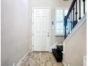 Bright foyer featuring wood-look tile flooring, staircase access to the second floor, and a front door at 4744 Wandering Way, Wesley Chapel, FL 33544