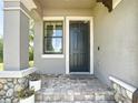 Close-up of the front door with stone accents, lush landscaping, and a window for natural light at 4744 Wandering Way, Wesley Chapel, FL 33544