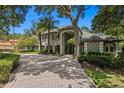 Beautiful home exterior with a circular driveway, arched entryway, and elegant landscaping at 6352 W Maclaurin Dr, Tampa, FL 33647