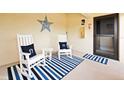 Inviting front porch with rocking chairs, a striped rug, and nautical decor for a coastal vibe at 7540 Sunshine Skyway S Ln # 217, St Petersburg, FL 33711