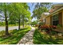 Scenic view of a home with a lush green lawn and mature trees alongside a tranquil lake at 9101 Crystal Commons Way, Tampa, FL 33626
