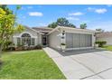 Inviting single-story home featuring a landscaped front yard and a two-car screened garage at 11026 Austin Ct, New Port Richey, FL 34654